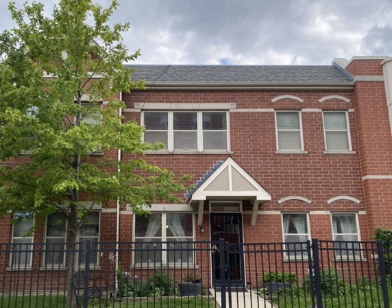 Front view of a two-story brick house with a triangular roof over the entrance.