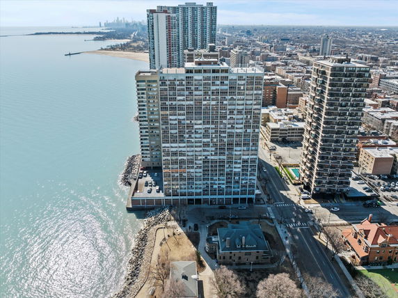 Aerial view of high-rise buildings along a lakeshore with urban landscape in the background.