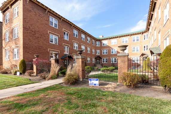 Front view of a multi-story brick building with gated entrance.