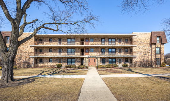 Front view of a three-story brick apartment building with balconies.