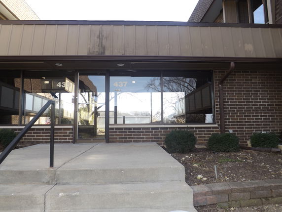 Front view of a building entrance with brick facade and large glass windows.