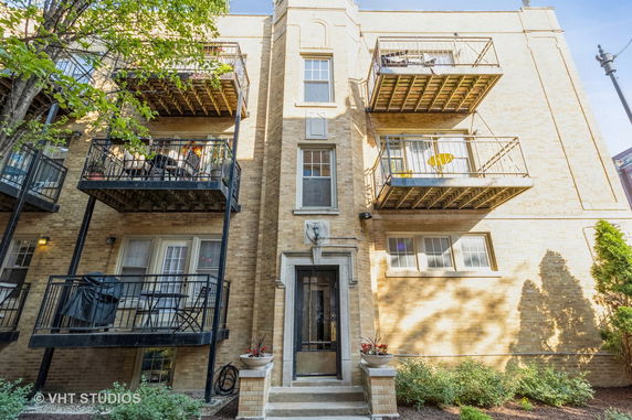 Front view of a multi-story brick apartment building with balconies.