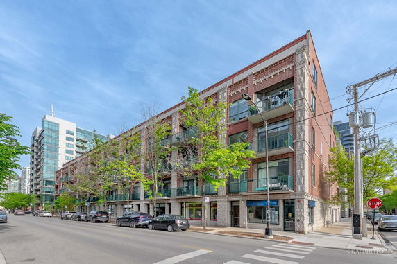 Front view of a multi-story building with shops on the ground floor and balconies on the upper levels.