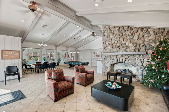 Interior view of a clubhouse with stone fireplace, seating area, and game table.