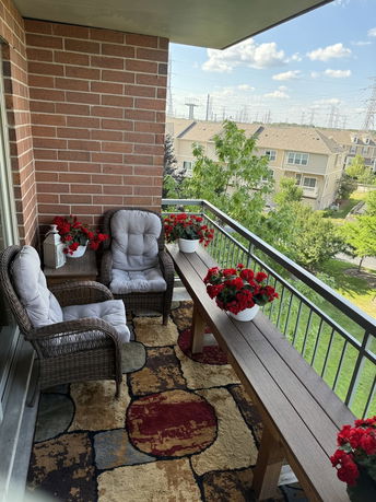 Balcony with wicker chairs and a table overlooking a residential area.