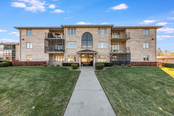 Front view of a multi-story residential building with balconies and a central entrance.