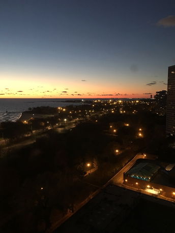 Wide angle view of a cityscape at twilight with streetlights and a body of water.