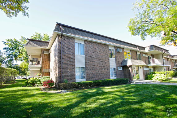 Front view of a two-story brick apartment building with balconies.