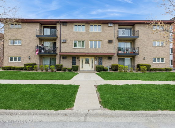 Front view of a three-story apartment building with balconies.