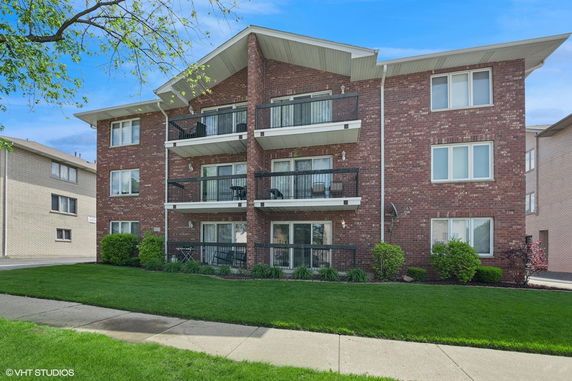 Front view of a brick apartment building with balconies.