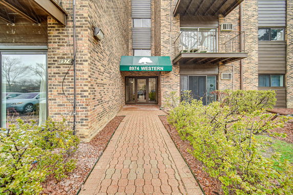 Front view of a brick building with a green awning over the entrance.