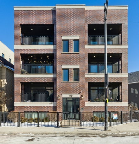 Front view of a four-story brick building with balconies.