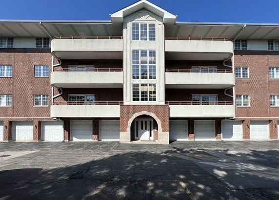Front view of a multi-story brick building with balconies and garages.