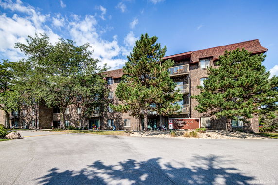 Front view of a multi-story brick apartment building with balconies.
