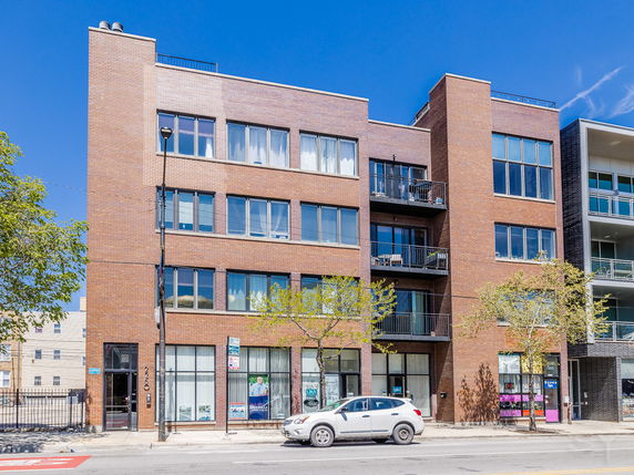Front view of a multi-story brick apartment building with large windows and balconies.
