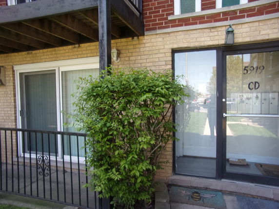 Front view of a building entrance with glass door and brick exterior.
