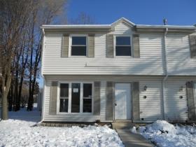 Front view of a two-story townhouse with white siding and windows.