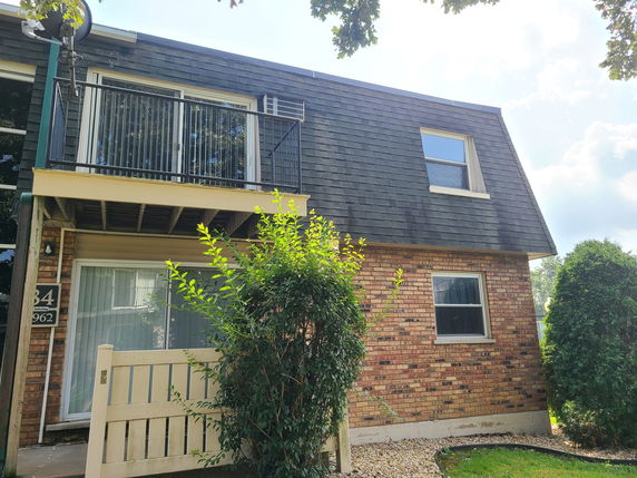 Front view of a two-story house with a brick facade and balcony.