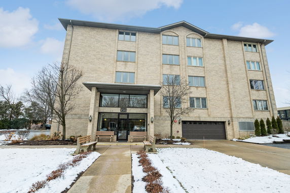 Front view of a multi-story brick building with large windows and a garage entrance.