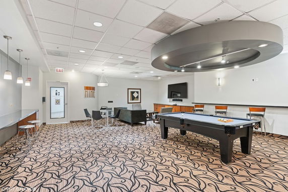 Room with a billiards table, seating area, and television.