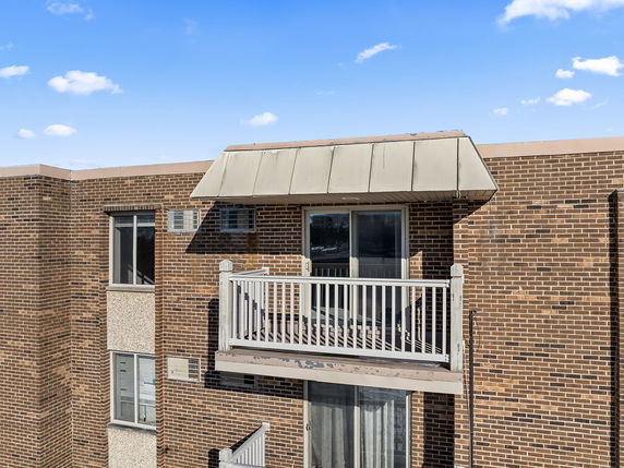 Front view of a multi-story brick building with a small balcony.