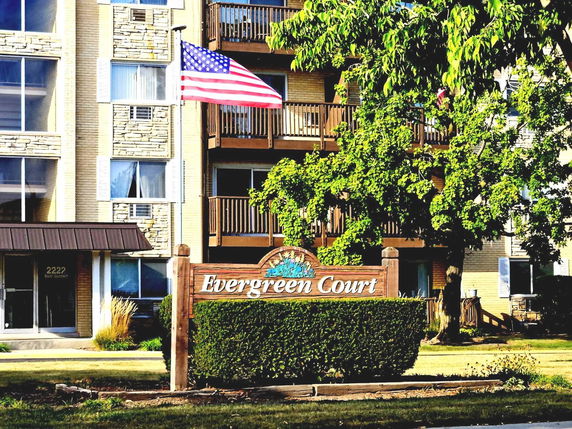 Front view of a multi-story residential building with balconies and a sign that reads 'Evergreen Court'.