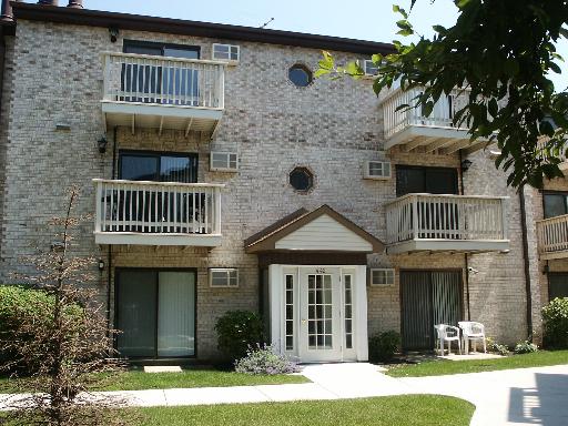 Front view of a three-story brick building with multiple balconies and a central entrance.