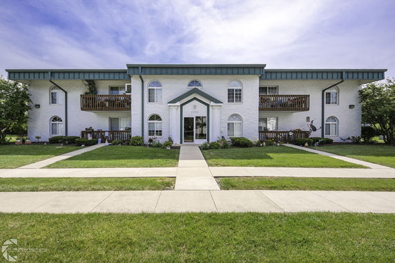 Front view of a white two-story building with balconies and green trim.