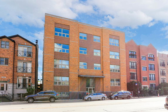Front view of a multi-story brick building with large windows.