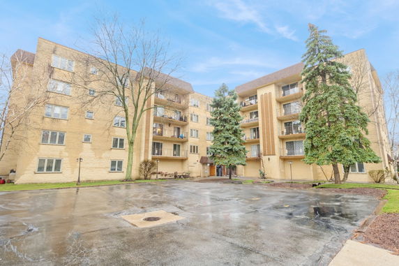 Front view of a multi-story residential building with balconies and a central entrance.