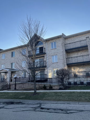 Front view of a multi-story brick apartment building with multiple balconies.