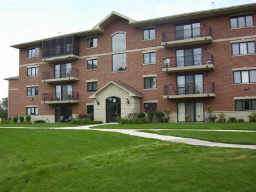 Front view of a multi-story brick apartment building with balconies.