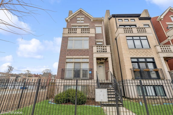 Front view of a multi-story townhouse with brick facade and steps leading to the entrance.