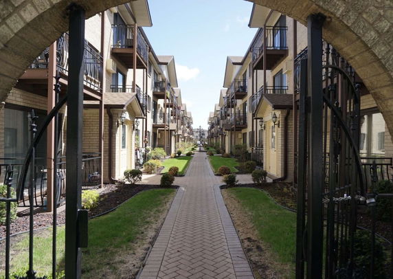 Front view of two rows of multi-story residential buildings with gated entrance.