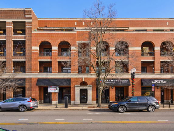 Front view of a multi-story brick building with commercial spaces on the ground floor.