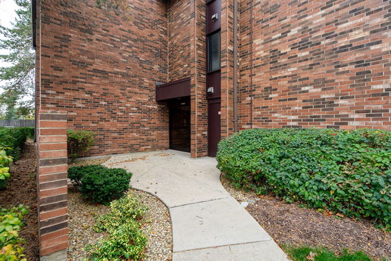 Exterior brick wall of a building with a path leading to a recessed entrance.