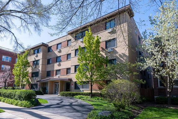Front view of a multi-story brick building with several windows and a covered entrance.