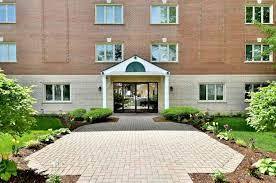 Front view of a multi-story building with a brick facade and entrance walkway.