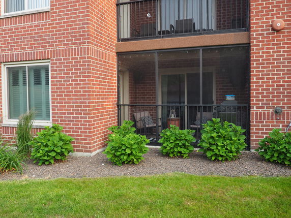 Front view of a multi-story brick building with a screened balcony.