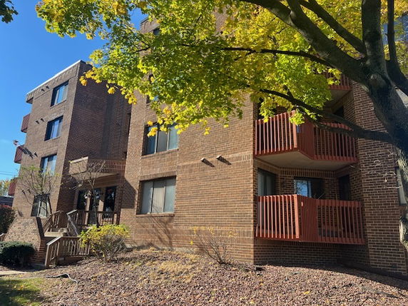 Front view of a multi-story brick apartment building with balconies.