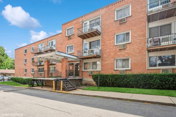 Front view of a brick apartment building with balconies and a covered entrance.