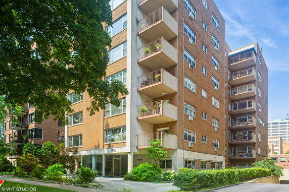 Front view of a multi-story brick apartment building with balconies.