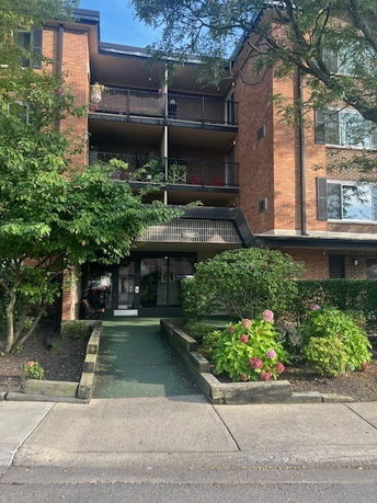 Front view of a multi-story brick apartment building with balconies.