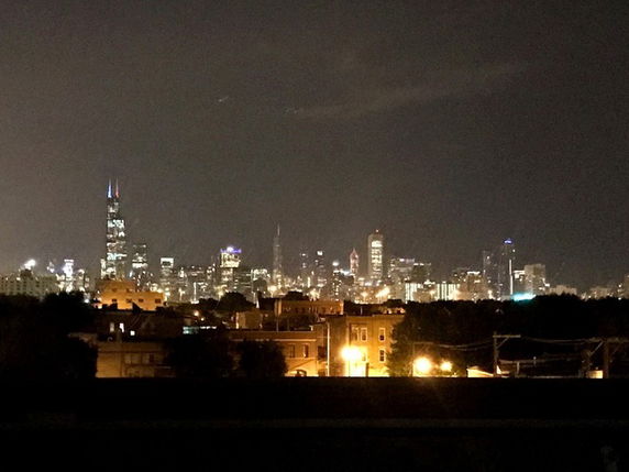 Nighttime panoramic view of a city skyline with illuminated skyscrapers.