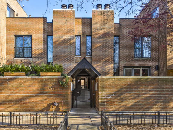 Front view of a modern two-story brick building with large windows and a gated entrance.