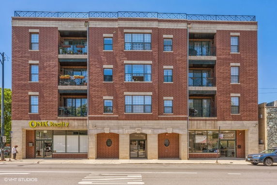 Front view of a multi-story brick building with commercial space on the ground floor.