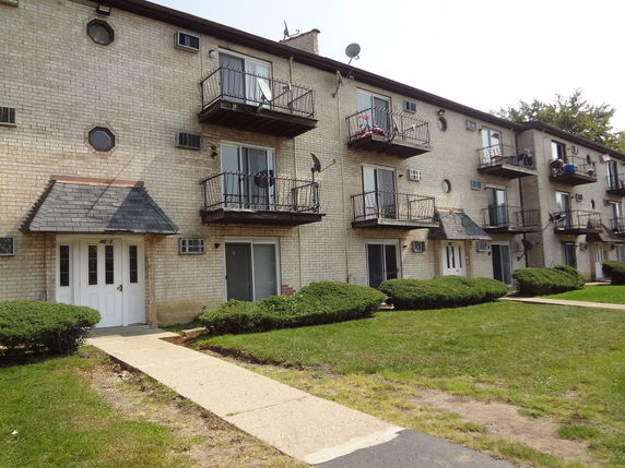 Front view of a three-story apartment building with balconies and entry doors.