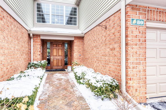 Front entrance of a house with a brick exterior and wooden door.
