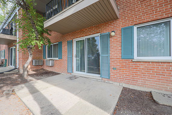 Front view of a brick building with sliding glass door and blue shutters.