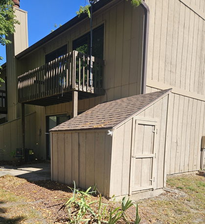 Front view of a two-story house with a small balcony and an attached shed.